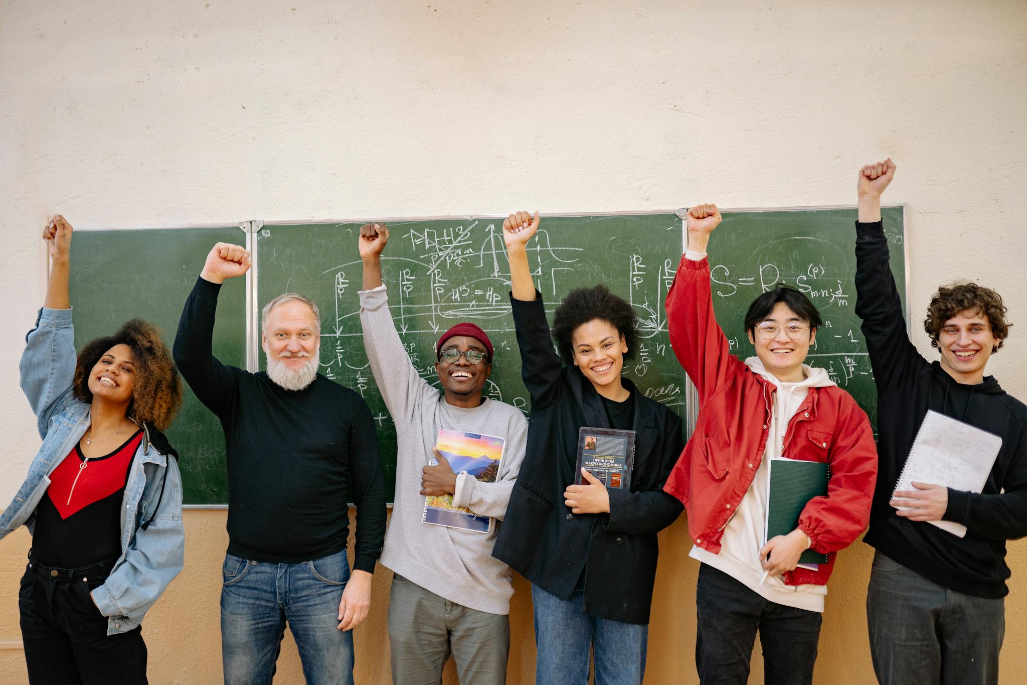 A cheerful group of diverse students and a teacher celebrating in front of a chalkboard full of equations.