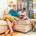 Father assisting son with homework in cozy living room setting, fostering learning and bonding.